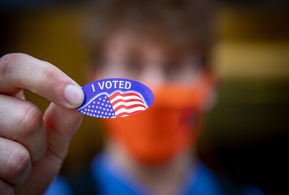 fingers holding 'I Voted' sticker